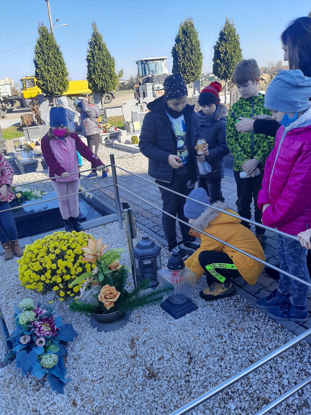 Uczniowie klasy 2 zapalają znicze na grobach nauczycieli